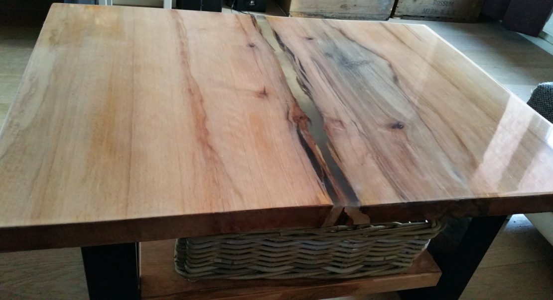 Industriële vintage eiken massief salontafel met epoxy coating, 2 schaaldelen massief eikenhout van ongeveer 5 cm dikte. Deze boomstamdelen zijn doormiddel van een strook epoxy giethars in het midden aan elkaar verbonden.
